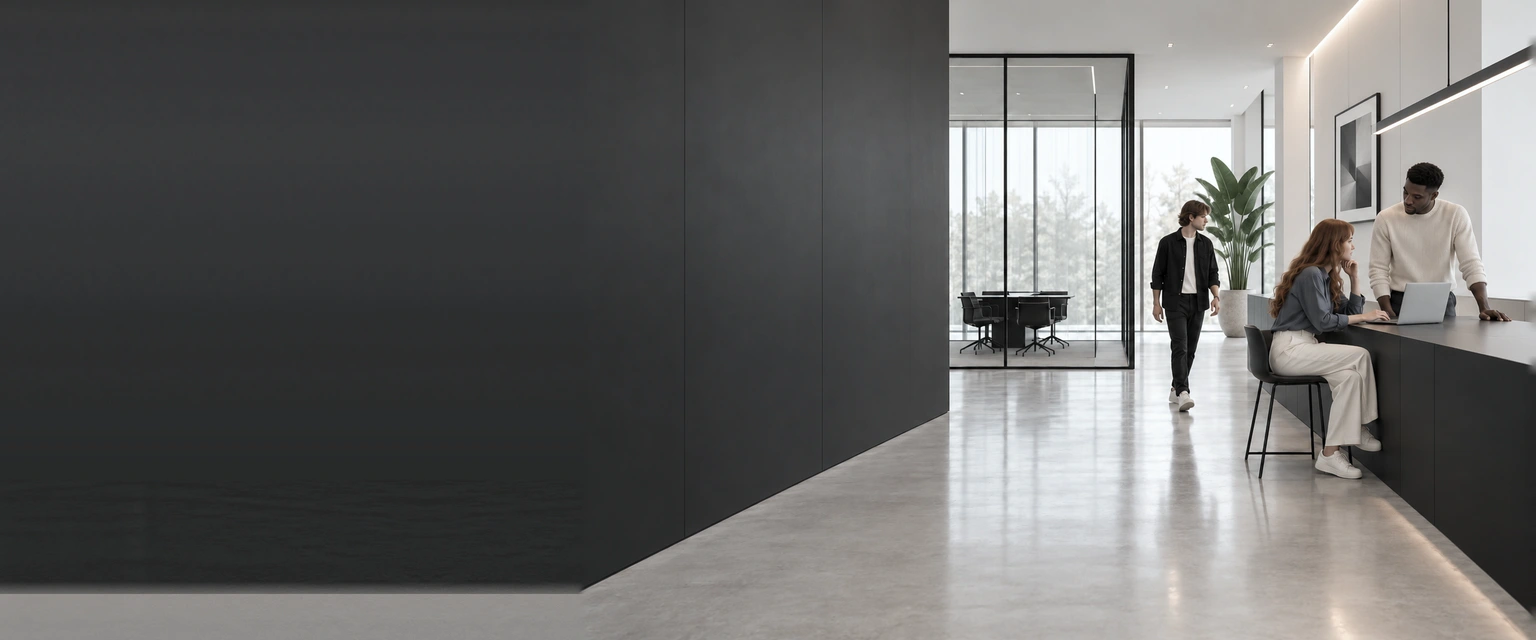 Colleagues talk at a minimal reception counter in a bright office.